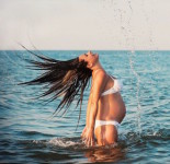 14425176 - pregnant woman splashing around in the sea